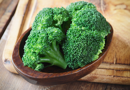 Bunch of fresh green broccoli on brown plate over wooden backgroundの写真素材