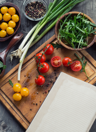 Cooking concept. Empty Recipe book surrounded of colorful fresh vegetables over wooden backgroundの写真素材
