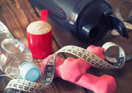weight loss concept with tape measure whey powder, pink dumbbells and black shakerの写真素材