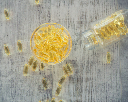 Omega 3-6-9 fish oil yellow softgels on wooden  board into  glass jarの写真素材