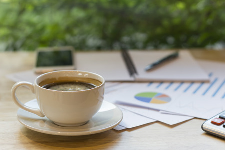 office desk workplace with coffee cup and charts on wooden tableの写真素材