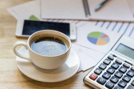 office desk workplace with coffee cup and charts on wooden tableの写真素材