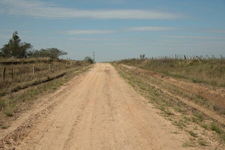 A dirt road that crosses a stretch of land amidst rural countryside. Interior of Brazil in the city of Jaguari, in the state of RS. Land of natural beauty.の写真素材