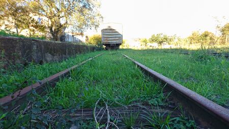 Train tracks and a stationary passenger car. Rail transport infrastructure. Wagon stopped at abandoned train station.の写真素材
