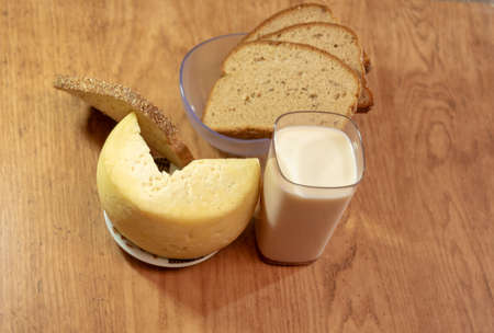 Table prepared for breakfast with a glass of milk, cheese and slices of bread. Human food. Products for consumption next to the afternoon coffee.の写真素材