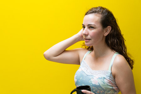 Blonde, Brazilian woman with curly hair drinks coffee from a porcelain cup. Female beauty. Latin American woman smiling and holding a cup in her hands enjoying a Brazilian coffee.の写真素材