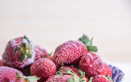 Frozen strawberries in close-up (Fragaria spp). frozen strawberries background. Fresh fruits covered with ice. Fruits arranged on a light background.の写真素材