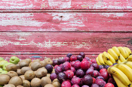 Tropical fruits. Scene background. fruits on wooden background. bananas, kiwis, plums and apples. Food for human consumption. Sales stall. Natural products.の写真素材