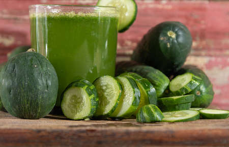 Juice and fresh fruits of green cucumber (Cucumis sativus). Wood background. Vegetables for salads....