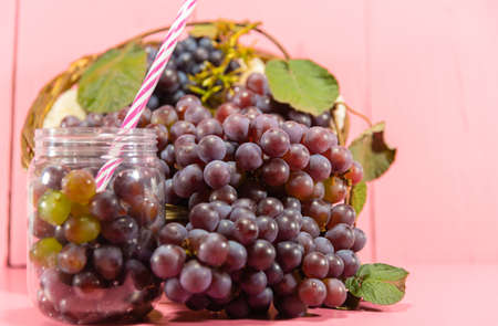 Pot with grains and grape clusters. Grape juice. refreshing drink. Fruit drink. Ingredient for wines and juices. Fresh fruits. Pink grape.の写真素材