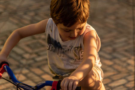 Image of a Caucasian Brazilian boy, descendant of Italian immigrants playing with his bicycle in the yard of his house. Childhood. Children's games and cycling sport.の写真素材