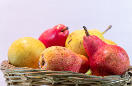 Pear fruits in wooden basket. Pink background. Fresh fruits. The pear (Pyrus communis L.) is a fruit...