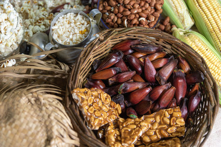 Wicker basket with typical Brazilian foods. June party foods. Pine nuts, brown sugar, peanuts, popcorn, green corn. Popular celebrations. Goodies and typical cuisine.の写真素材