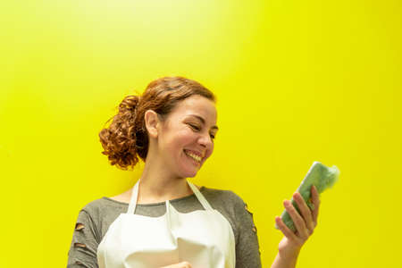 Young Brazilian woman. Woman in an apron on yellow background. Profession and technology. Blonde...