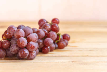 Bunch of pink grape and glass of natural juice. Wood background. Table grapes ready for consumption. Crystal with grape juice. Fruit for making juices and jams. Vine product. Detox berries.の写真素材