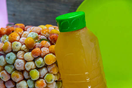 Bottle of acerola juice anchored in a tower of frozen acerola fruits. Detox drink and rich in vitamin c. Exotic fruit. Natural energetic. Natural and anti-flu juice.の写真素材