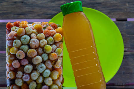 Bottle of acerola juice anchored in a tower of frozen acerola fruits. Detox drink and rich in vitamin c. Exotic fruit. Natural energetic. Natural and anti-flu juice.の写真素材