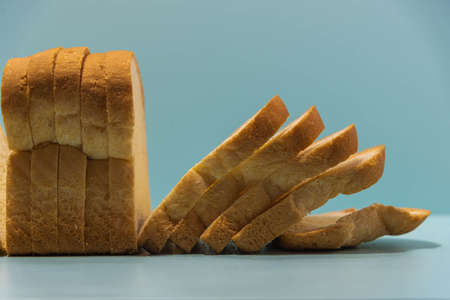 Industrial bread on blue background. Loaf bread. Loaf of bread is a product obtained from cooking the sweet dough of wheat flour. Gluten-based food.の写真素材