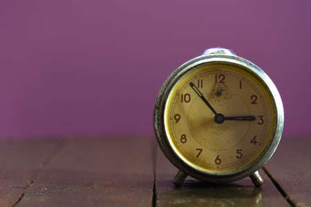 Old and retro alarm clock on wooden surface. Vintage background. Decor object. Time marker. Analog clock. Clock on dark background.の写真素材