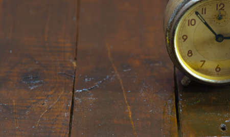 Old and retro alarm clock on wooden surface. Vintage background. Decor object. Time marker. Analog clock. Clock on dark background.の写真素材
