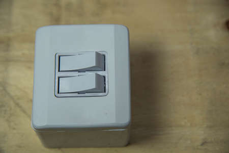 Double switch electrical switch on wooden background. Electric material. Utensil for installation of electrical network. Wall plug. Residential lamp switch.の写真素材