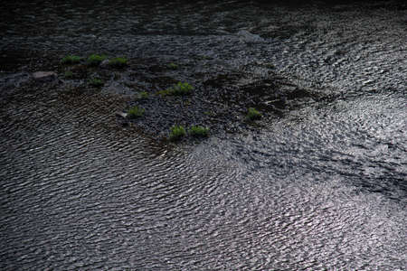 Small stream reflecting the colors of the evening and dramatic sky in Brazil. Abstract landscape and...