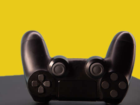 Black joystick on a yellow background, close-up. Gamepad on a yellow background.