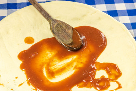 Homemade pizza preparation with tomato sauce. Homemade Pizza. Italian cuisine. Amateur cuisine. Food. Typical food preparation. Homemade pasta with tarantella sauce spread by wooden spoon.の写真素材