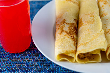 Rolled pancakes served on the table. Pancake is a type of dough fried in little oil on a hot plate or skillet, basically made with eggs, flour and milk.の写真素材