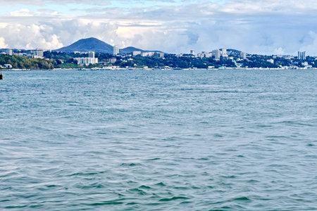 panorama of the Black Sea with a mountain landscape and a modern city on the horizon, during a cloudy sunsetの写真素材