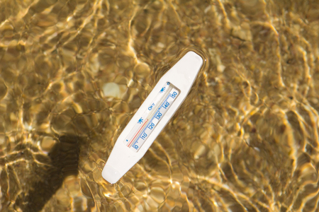 water thermometer in water measures the warm water of the red sea against the background of the sandy bottom view from the topの写真素材