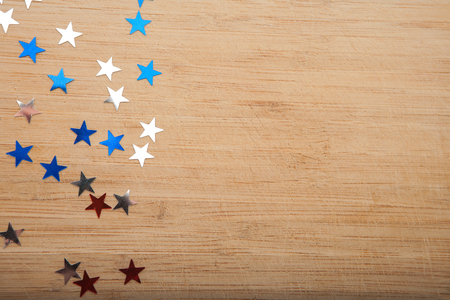 Confetti stars on wooden background. 4th July, Independence day, card, invitation in usa flag colors. Top view, empty space.の写真素材