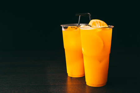 Photo of two orange lemonades on dark table over black background.の写真素材
