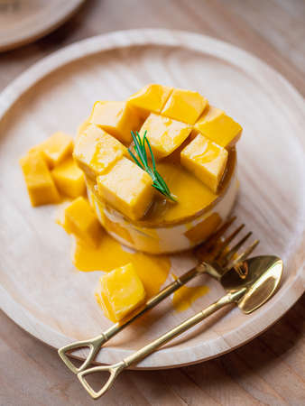 Sweet Yellow Mango dessert, cheesecake. Ripe yellow mango cheesecake serves on the round wooden tray...