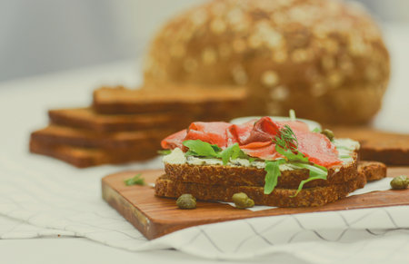 Smoked salmon sandwich with cheese, pistachio and salad leaves, brown breadsの写真素材