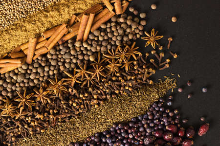 Aromatic spices and herbs on black table. Seasonings background for design packaging of food or...
