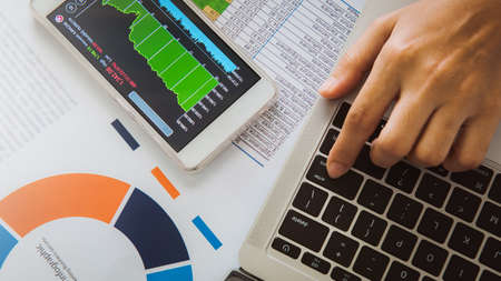 Businesswoman analyze business report graph and finance chart using smartphone and computer laptop...