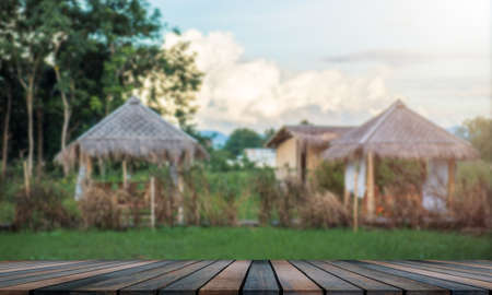 Empty wooden table, blurred background of the garden, and a small houseの写真素材
