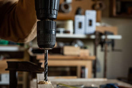 Carpenter making a drill with a spinning top on a wooden boardの写真素材