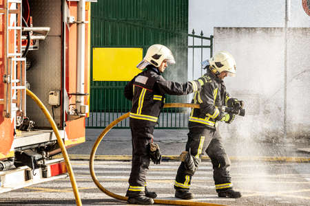 firefighters with a water hose pulling water to put out a fireの写真素材