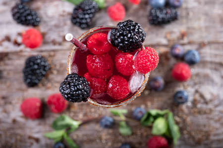 forest fruit cocktail in a glass seen from above on a wooden base decorated with blackberries