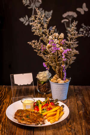 Grilled steak with french fries and vegetables served on a wooden tableの写真素材