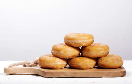 wooden board with doughnuts stacked on top of each other forming a pyramid on a white background