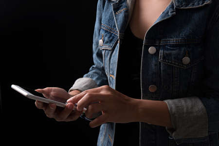 Young woman using mobile phone isolate on black backgroundの写真素材