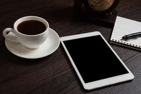 Tablet and coffee cup and blank notebook for memo with pen on wooden background. Business and object...