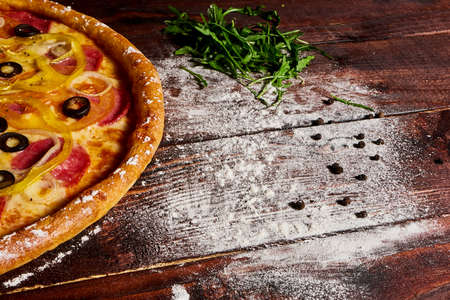 Wooden kitchen table with pizza sprinkled with flourの写真素材