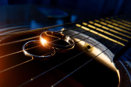wedding rings on guitar strings close-up on a dark background.の写真素材