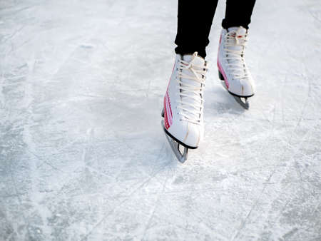 Woman skating and training with white skates on the ice area in winter day. Weekends activities outdoor in cold weather.の写真素材