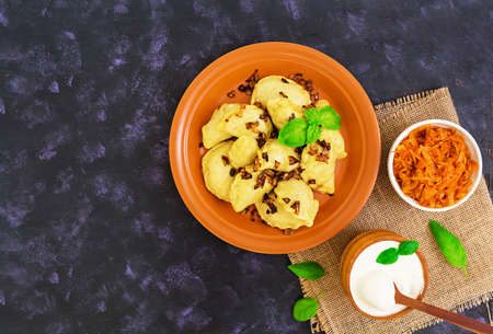 Delicious dumplings with cabbage and sour cream on dark background. Top view