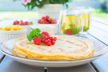 Pancakes with caramelized apples, raspberries, strawberries and red currants. Brunch with green tea...